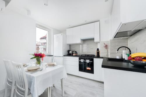 una cocina con armarios blancos y una mesa y sillas blancas. en Bella Casa Premium Apartment - 117A Kobierzynska, en Cracovia