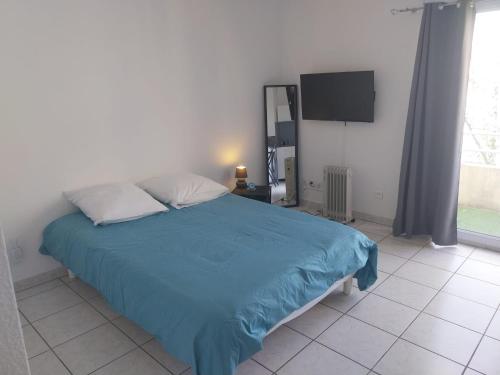 a bedroom with a bed with a blue blanket and a tv at Studio dans résidence avec piscine in Montpellier