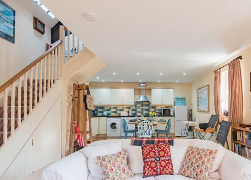 a living room with a white couch and a kitchen at The Old Schoolroom by Bloom Stays in Canterbury