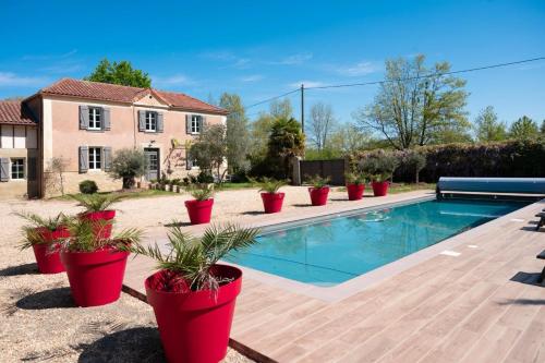 une maison avec une piscine et des plantes en pot dans l'établissement La Bastide 1767 Villa de charme avec piscine 15x5, climatisation, 4 chambres, cuisine extérieur, à Saint-Mont