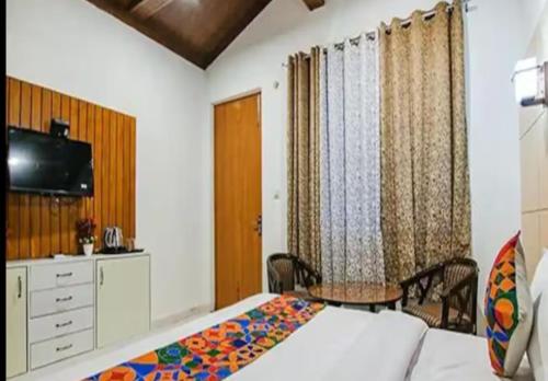 Schlafzimmer mit einem Bett, einem Tisch und einem TV in der Unterkunft HOTEL GLOBAL CORPORATE NOIDA in Noida