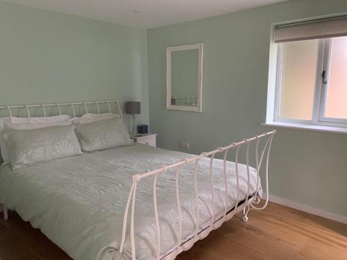 1 dormitorio con 1 cama blanca con marco metálico en Brand new annexe on border of the Southdowns., en Waterlooville