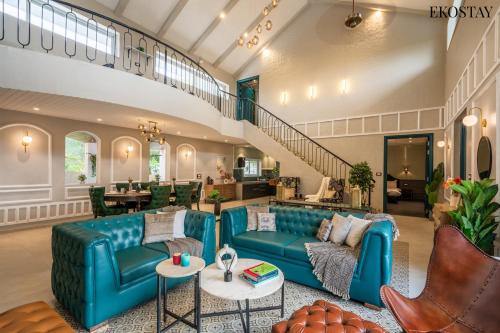 a living room with blue couches and a staircase at EKOSTAY Luxe - CASABLANCA VILLA in Igatpuri