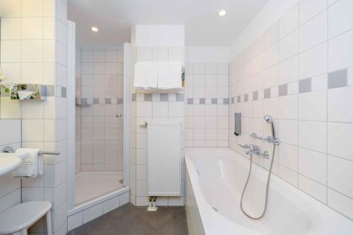 La salle de bains est pourvue d'une baignoire, d'une douche et d'un lavabo. dans l'établissement PLAZA INN Köln Pulheim, à Pulheim