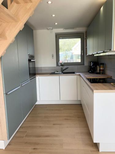 une cuisine avec des armoires blanches et une fenêtre dans l'établissement La cabine du bout du monde avec Mezzanine - Ile de Sein - votre maison de vacances de haut standing - PL03, à Crozon