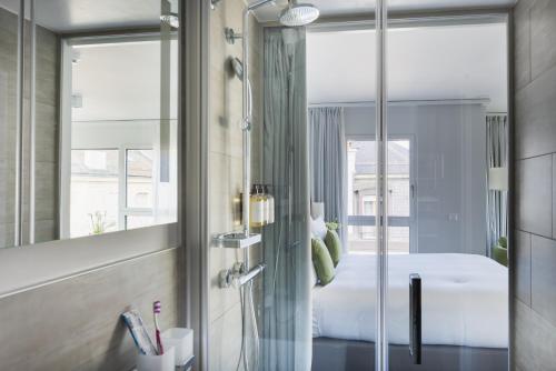 ein Bad mit einer Dusche, einem Bett und einem Spiegel in der Unterkunft Base Nyon in Nyon
