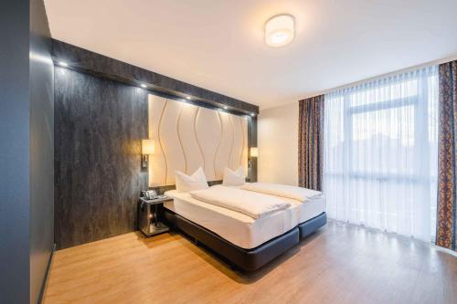 プルハイムにあるPLAZA INN Köln Pulheimのベッドと大きな窓のある寝室