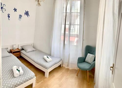 Cette chambre dispose de deux lits, d'une chaise et d'une fenêtre. dans l'établissement Saint Philippe - T3 Terrasse près de la plage, à Nice