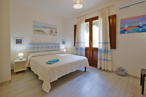 ein Schlafzimmer mit einem weißen Bett und einem Fenster in der Unterkunft Ma.Vi Casa Vacanze in Teulada