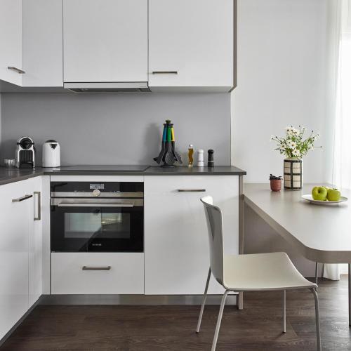 a kitchen with white cabinets and a table and chairs at Base Nyon in Nyon