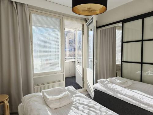 a bedroom with two beds and two windows at Modern One-Bedroom with glazed sun balcony, 350m metro in Helsinki