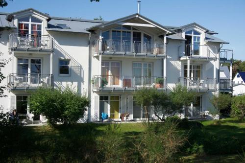 a large white building with balconies and trees at Am Strand in Juliusruh