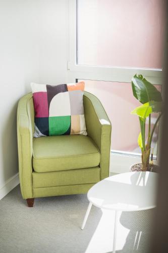 a green chair with a colorful pillow in a living room at Base Nyon in Nyon