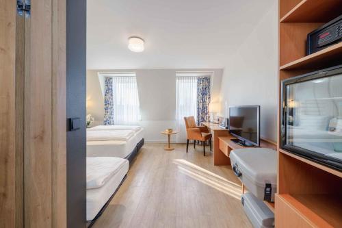 プルハイムにあるPLAZA INN Köln Pulheimのベッド2台とテレビが備わるホテルルームです。