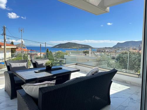 patio con mesa y sillas en el balcón en Kasaj Luxury Apartments, en Porto Rafti