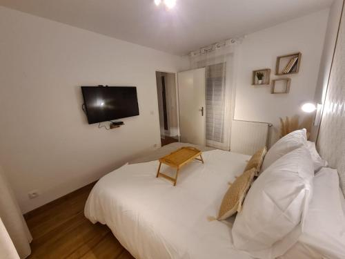Cette chambre comprend un lit blanc et une télévision murale. dans l'établissement La Boheme- Free Parking-Paris-Disneyland-Easy Check-in- Netflix, à Rosny-sous-Bois