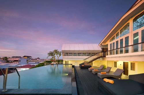 a swimming pool with couches and a building at Fashion Hotel Legian in Legian