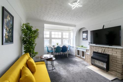 a living room with a yellow couch and a fireplace at Open Mind Property - Southsea with Free Parking in Portsmouth