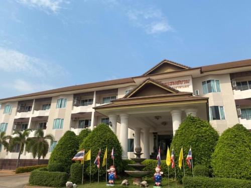 a building with flags and bushes in front of it at Siamtara Palace Hotel in Maha Sarakham