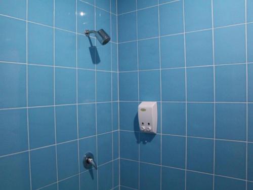 baño de azulejos azules con ducha y dispensador de jabón en The Grace Residence, en Surin