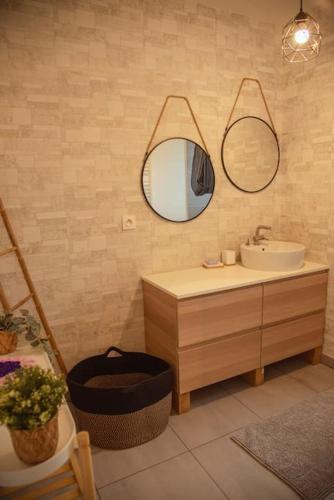 une salle de bain avec un lavabo et deux miroirs au mur dans l'établissement Maison Nouméa, à Saubrigues