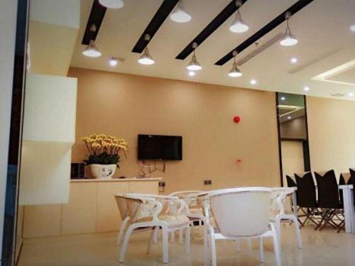 a room with a table and chairs and a tv at 7 Days Premium Huizhou Boluohu Town Luofu Mountain Branch in Henghe