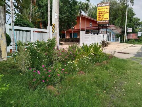 Farmesland Resort & Spa في Ban Thung Phai: حقل من العشب مع الزهور أمام المبنى