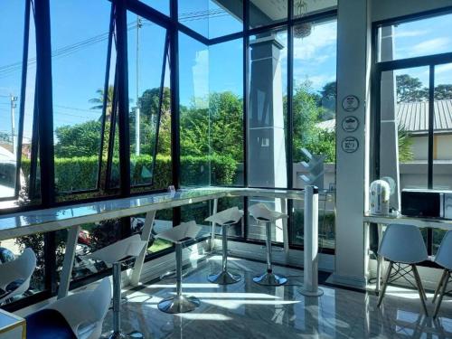 um quarto com cadeiras brancas, mesas e janelas em โรงแรม ไอยรา ริเวอร์ไรน์ นครพนม (AIYARA RIVERINE) em Ban Nong Puk