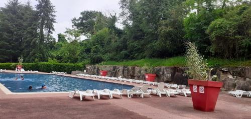 - une piscine avec des chaises blanches et des personnes qui s'y baignent dans l'établissement Bungalow charmant avec piscine partagée à Saint-Chéron, à Saint-Chéron