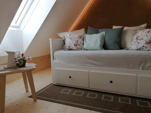 uma cama branca com almofadas e uma mesa num quarto em Ferienwohnung am Bio-Bauernhof Brandner em Schoberegg