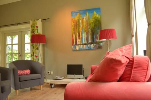 un soggiorno con divano rosso e TV di Stania State a Oenkerk