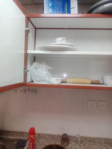 a kitchen shelf with dishes and other items on it at ORIENT TOWER STUDIO in Ajman 