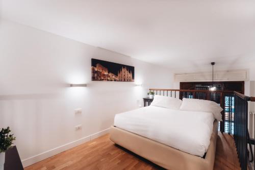 ミラノにあるCharming De Togni Apartmentの白いベッドルーム(ベッド1台付)が備わります。壁には絵画が飾られています。