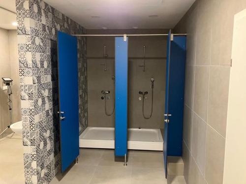 ein Badezimmer mit einer Dusche und einer Badewanne mit blauen Türen in der Unterkunft CafDorm in Maribor