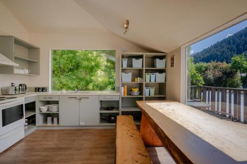 a kitchen with a wooden table and a large window at Haka House Queenstown in Queenstown