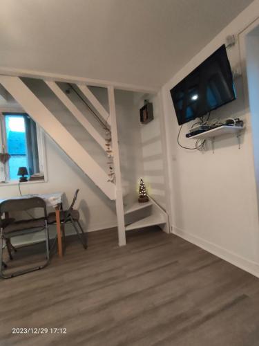 - un salon avec un escalier et une télévision murale dans l'établissement TANAGRA à Langrune-s-mer : 4 personnes, à Langrune-sur-Mer