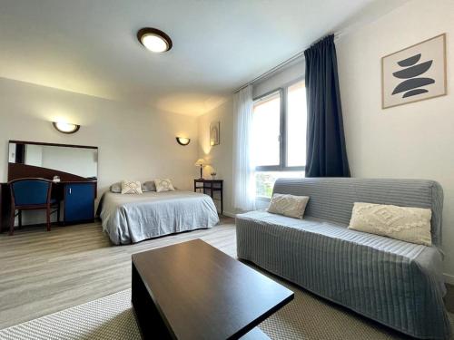 een woonkamer met een bank en een bed bij Zen studio ※ parking - piscine in Carcassonne