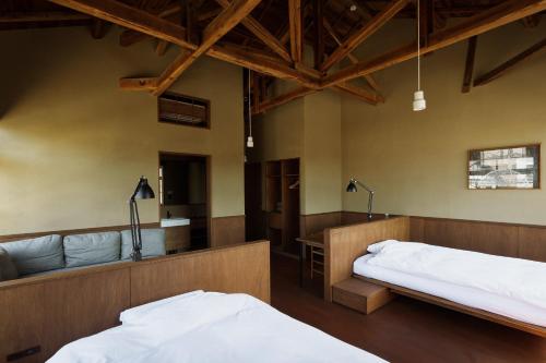 two beds and a couch in a room with wooden ceilings at awai 戸隠 in Nagano
