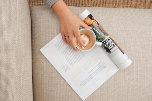 a woman holding a cup of coffee and a magazine at Urban Suites in Eindhoven