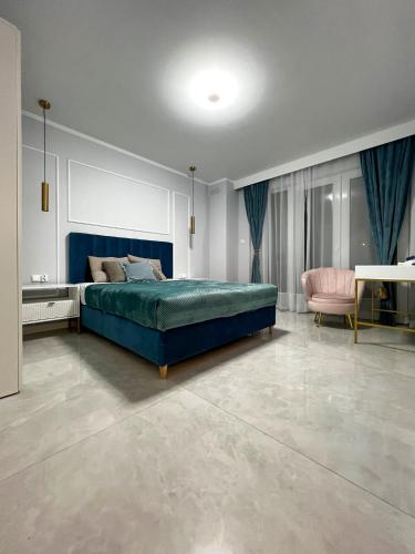 a bedroom with a blue bed and a pink chair at PaVoni Apartments Veranda Blu Mare in Łeba