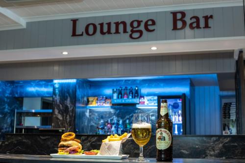 a bar with a glass of beer and a plate of food at Best Western Manor Hotel in Gravesend