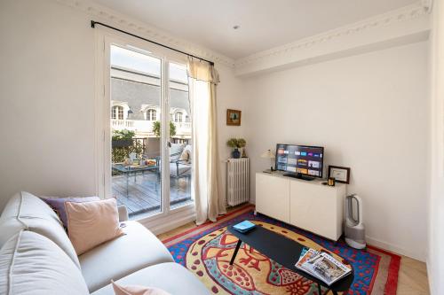 - un salon avec un canapé blanc et une télévision dans l'établissement Superb flat with terrasse & 24-7 security in the heart of Paris!, à Paris