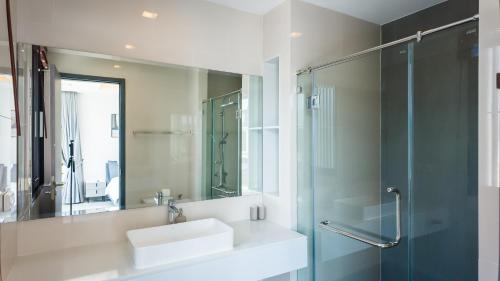 ein Bad mit einem Waschbecken, einer Dusche und einem Spiegel in der Unterkunft Laguna Park Villa in Phuket