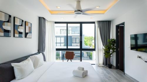 Schlafzimmer mit einem weißen Bett und einem Deckenventilator in der Unterkunft Laguna Park Villa in Phuket