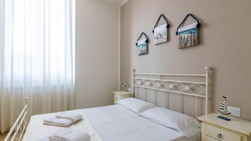 a white bedroom with a bed and three pictures on the wall at Villa Contessina in Cossignano