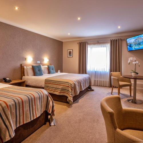 a hotel room with two beds and a tv at The Lodge Hotel in Coleraine