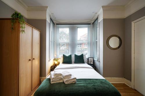 a bedroom with a bed with green sheets and a window at Two Bedroom Apartment in London Harlesden in London