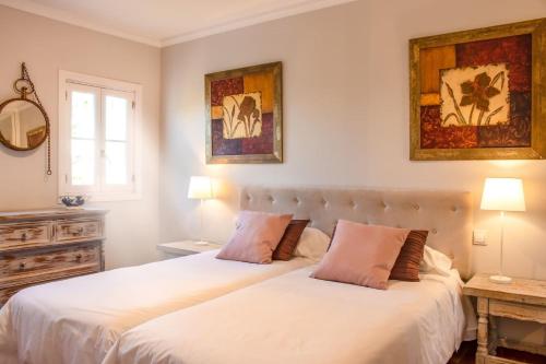 2 camas en un dormitorio blanco con 2 lámparas en Una casita en el campo dentro de la ciudad en Ávila