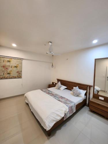 1 dormitorio con 1 cama grande y espejo en Anandi Service Apartment, en Pune