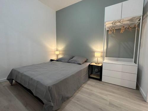 Cette chambre comprend un lit avec deux lampes et une commode. dans l'établissement Pasteur, appartement fonctionnel en centre-ville, à Lorient
